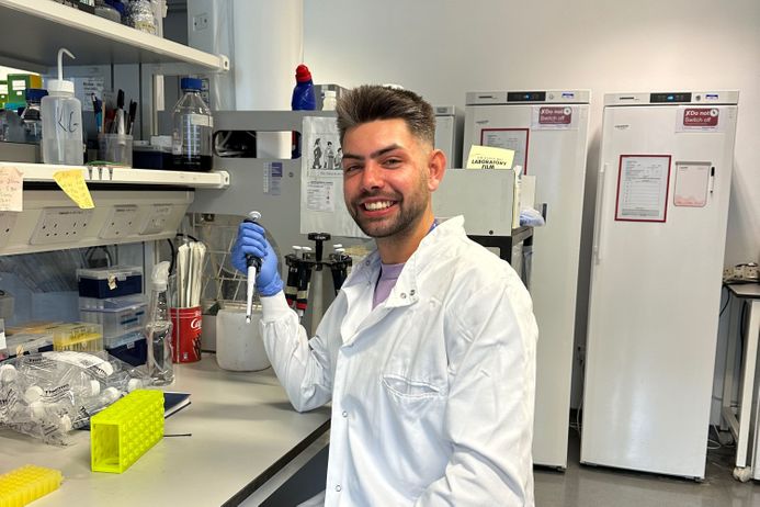 Student sitting in a lab with a white coat