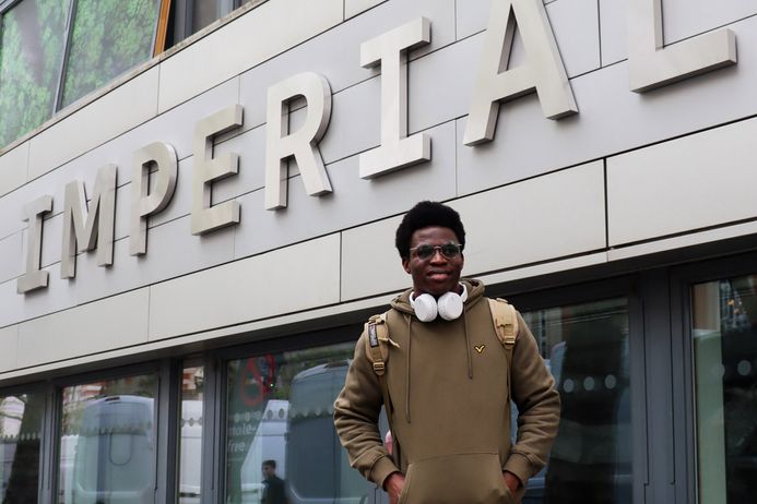 A student standing in front of the main building entrance at Imperial's South Kensington campus