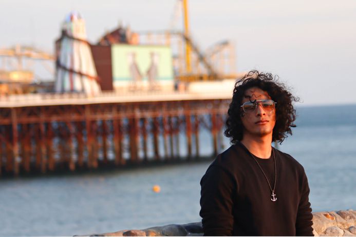 portrait of a male student in front of a pier leading out to sea