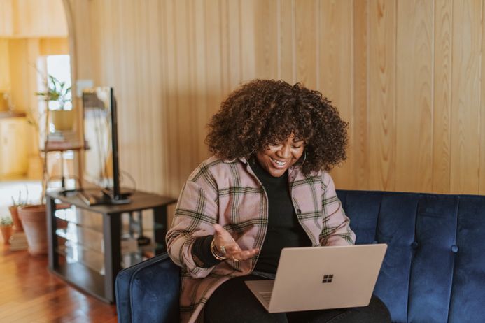 A student sitting on a sofa, using a laptop