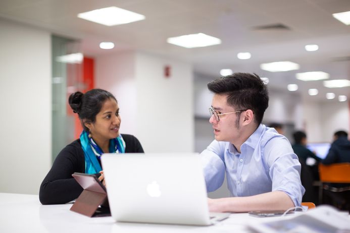 A woman and a man in conversation next to a silver laptop