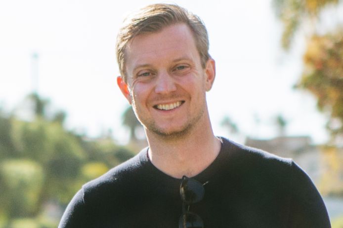 Christopher Hopper wears a white shirt and smiles to the right of the camera
