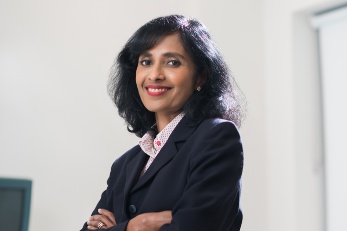 Reeba Oliver wears a suit and looks to camera with her arms folded
