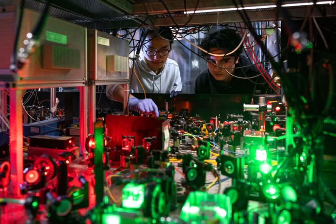 Two Imperial scientists examine lasers on an optical table