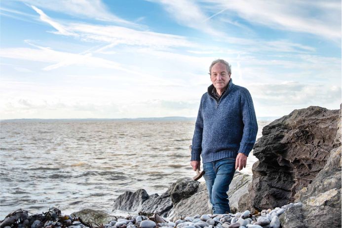 Stephen standing on a rock formation with the sea in the background