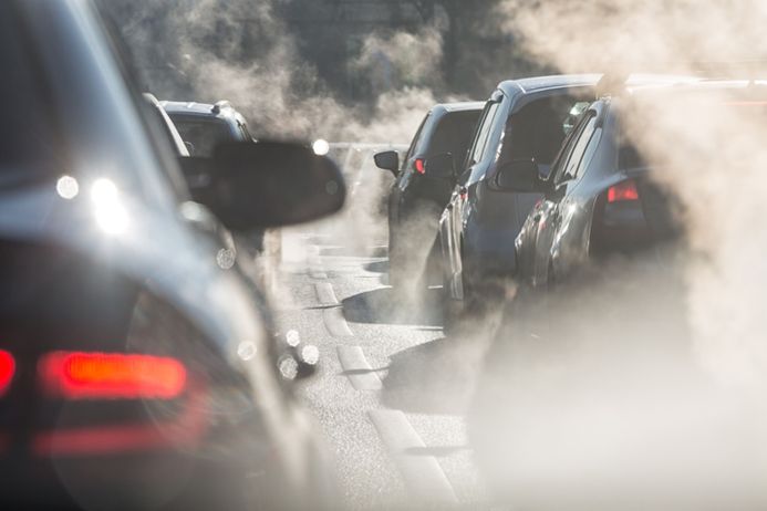 blurred silhouette of cars surrounded by exhaust fumes