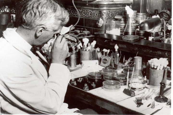 A photo of a Researcher looking through a microscope