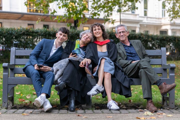A family, sitting on a bench after celebrating a students graduation