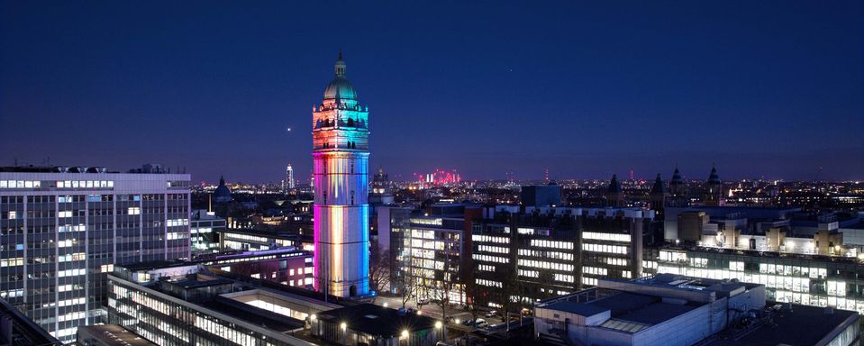 Queens tower lit up with a rainbow of lights, at night