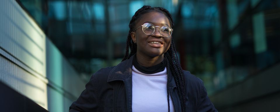 An undergraduate student stands and smiles on Dalby Court