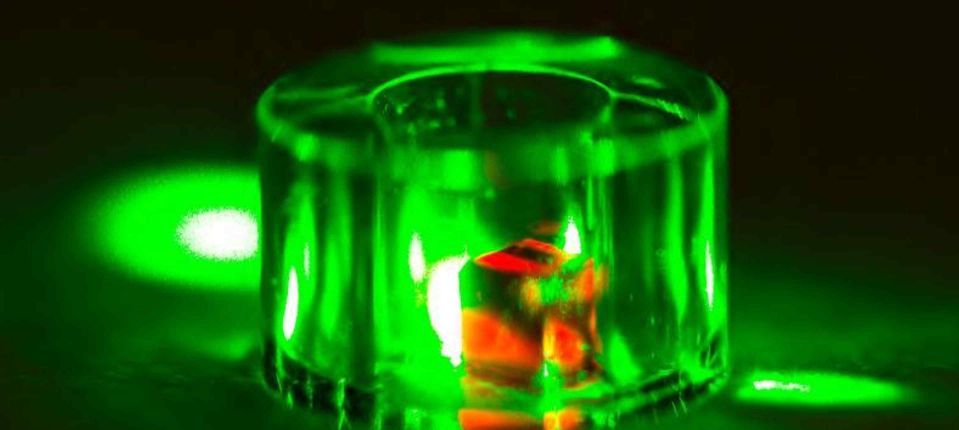 A diamond inside a sapphire ring lit by a green laser.