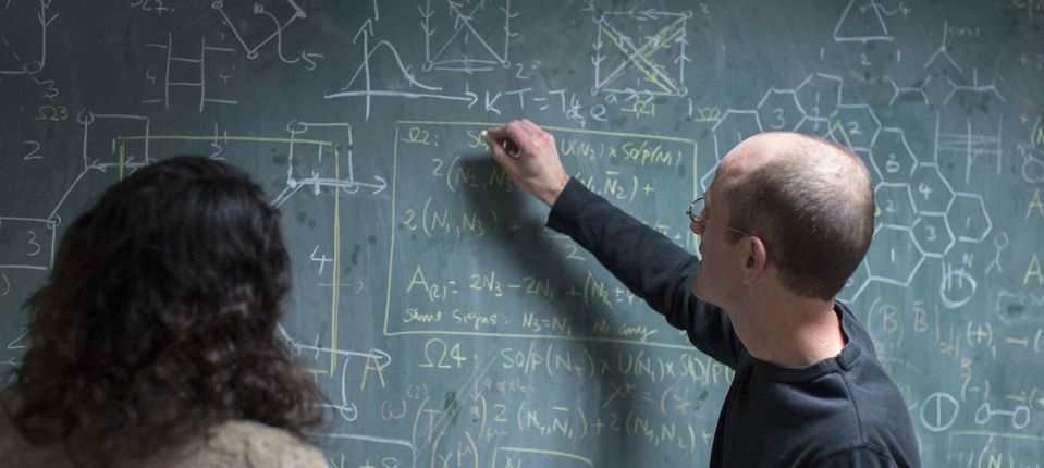 Professor Jerome Gauntlett discusses string theory equations with a research postgraduate.
