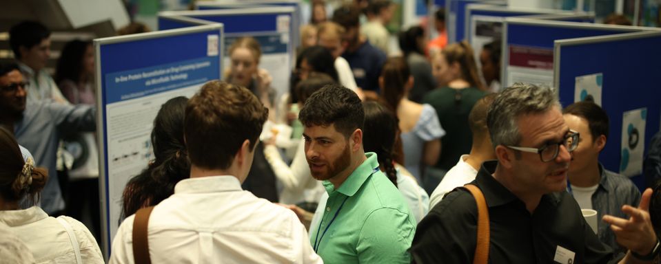 A group of students and academics talking around posters