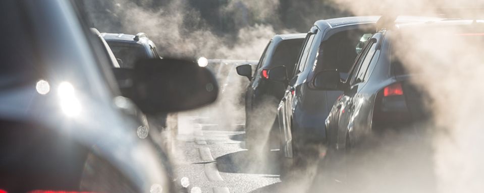 blurred silhouette of cars surrounded by exhaust fumes