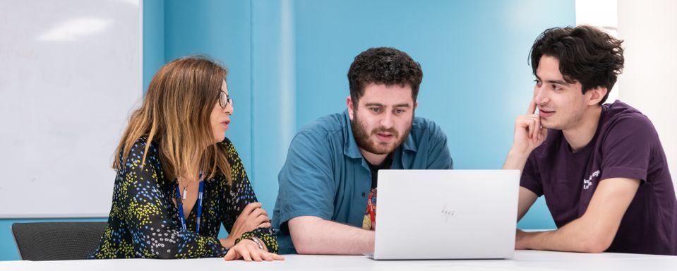 A CfAE coach and two students talking in front of a laptop