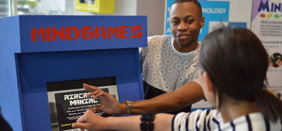 A student demonstrates a brain-controlled computer game to a visitor to the Imperial Festival