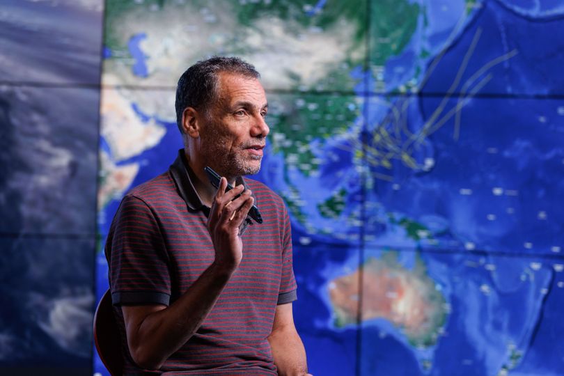 Professor Toumi sitting in the Data Science Institute with an image of the map on screen behind him