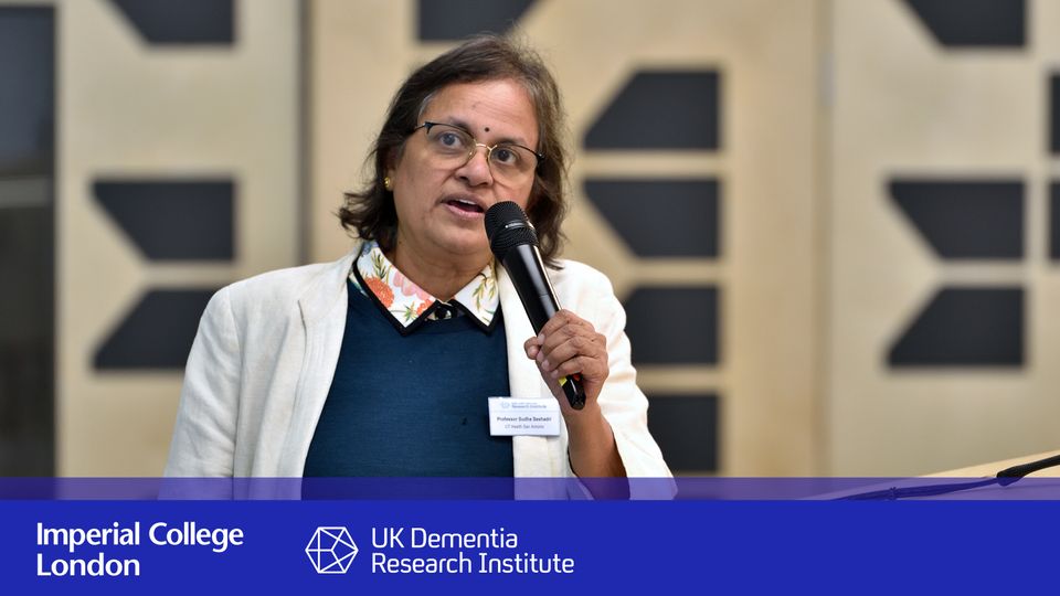 Sudha Seshadri speaks holding microphone to room at UK DRI conference