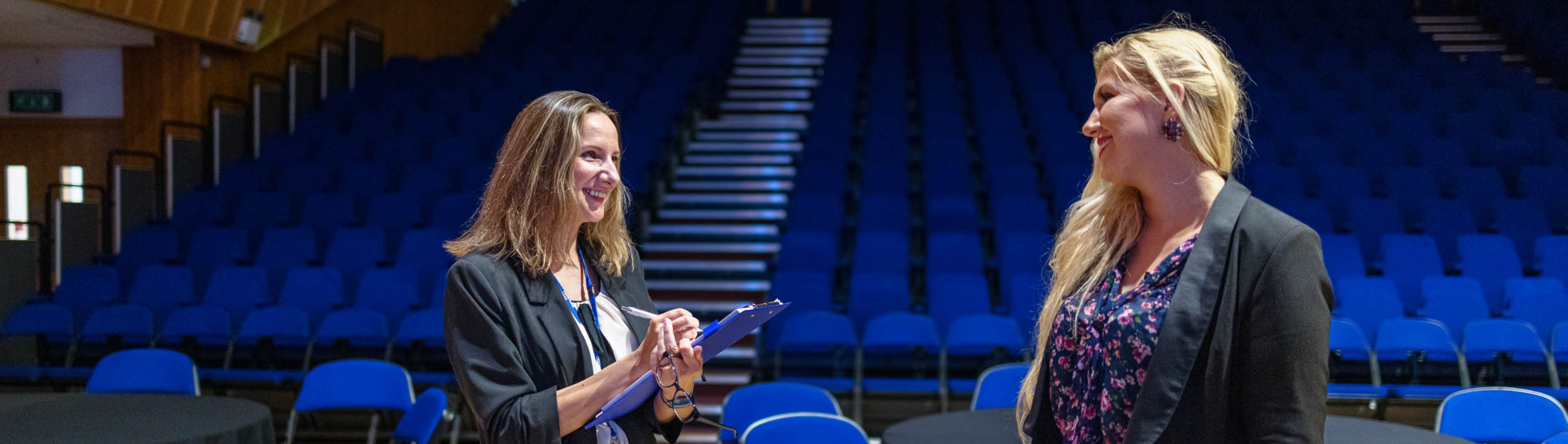 event management, two people in empty lecture theatre smiling