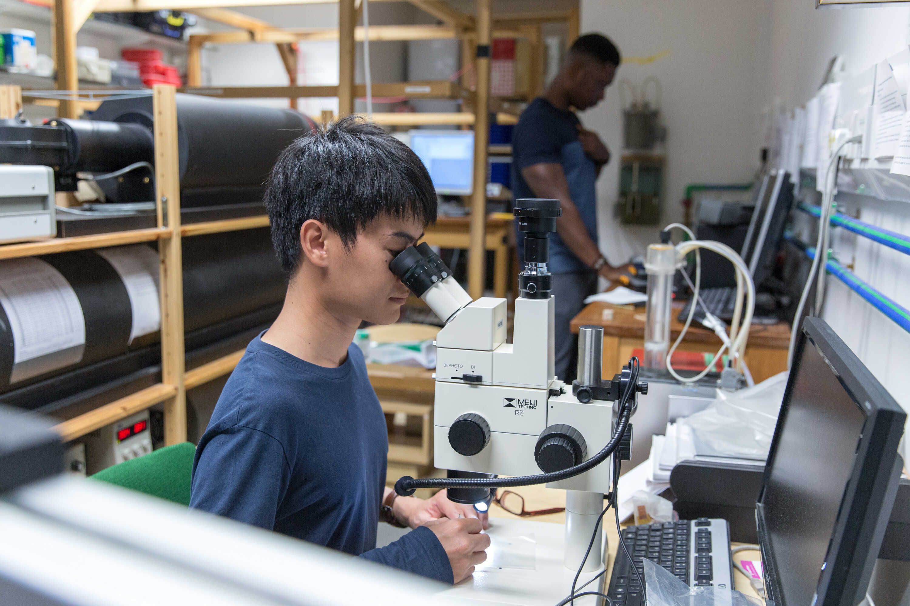 PhD students Sope Badejo and Radchagrit Supakulopas at work in the Palaeomagnetics laboratory working on palaeointensity experiments to determine Earth’s past magnetic field and picking minerals under the microscope
