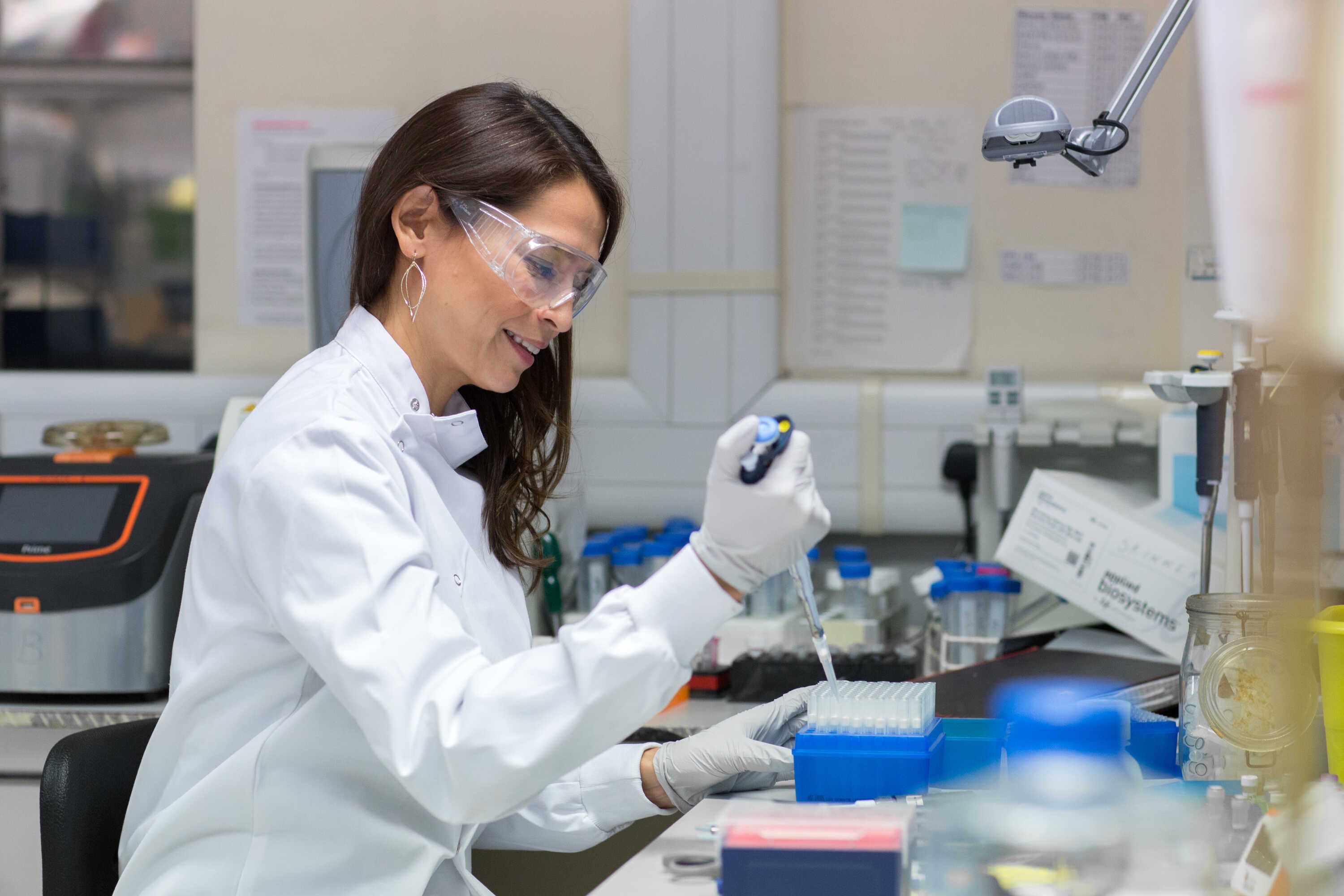 Dr Vanessa Sancho-Shimizu uses a pipette in the lab, wearing a lab coat