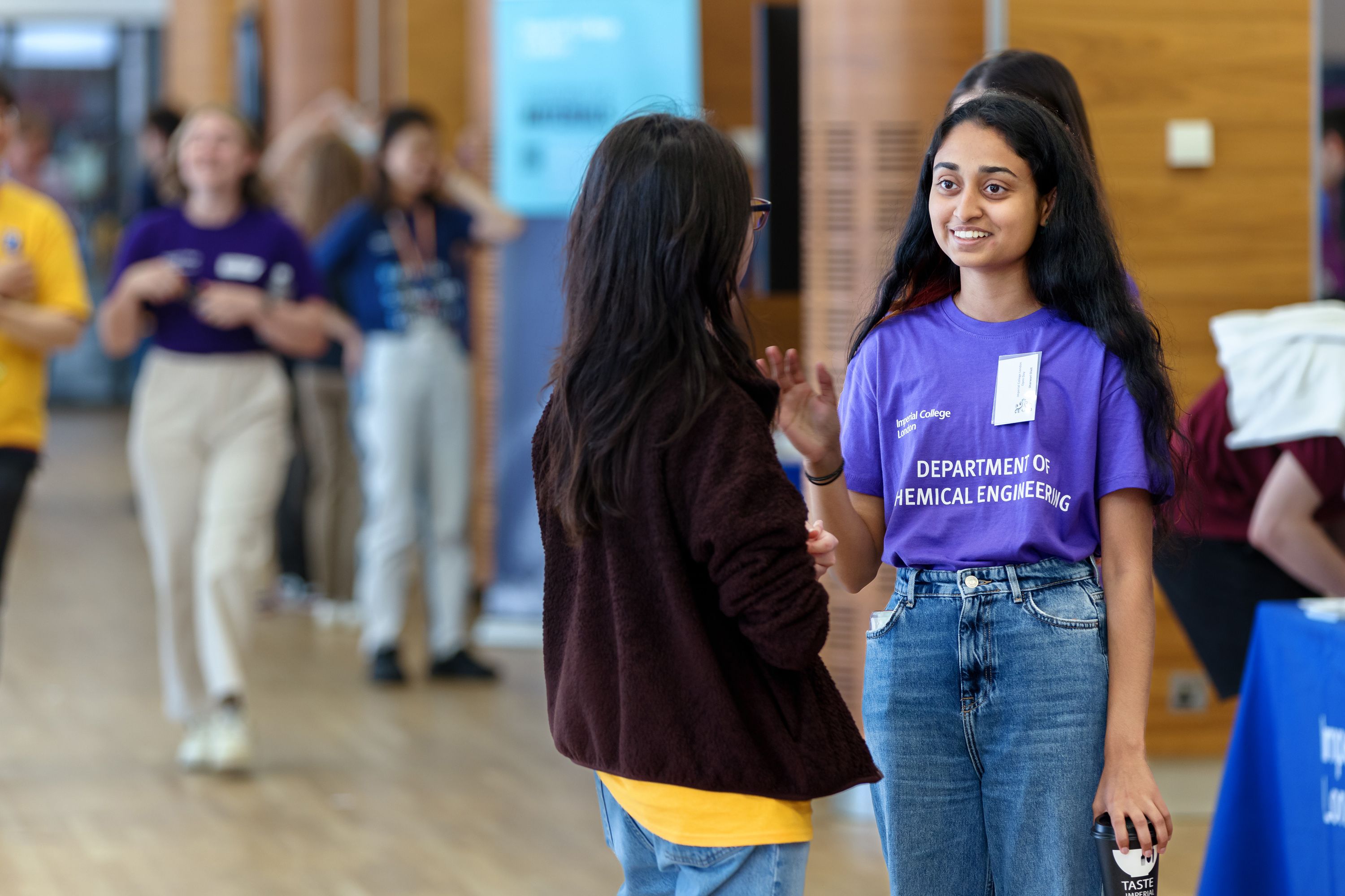 A woman in a purple Department of Chemical Engineering T-shirt speaks to a prospective student