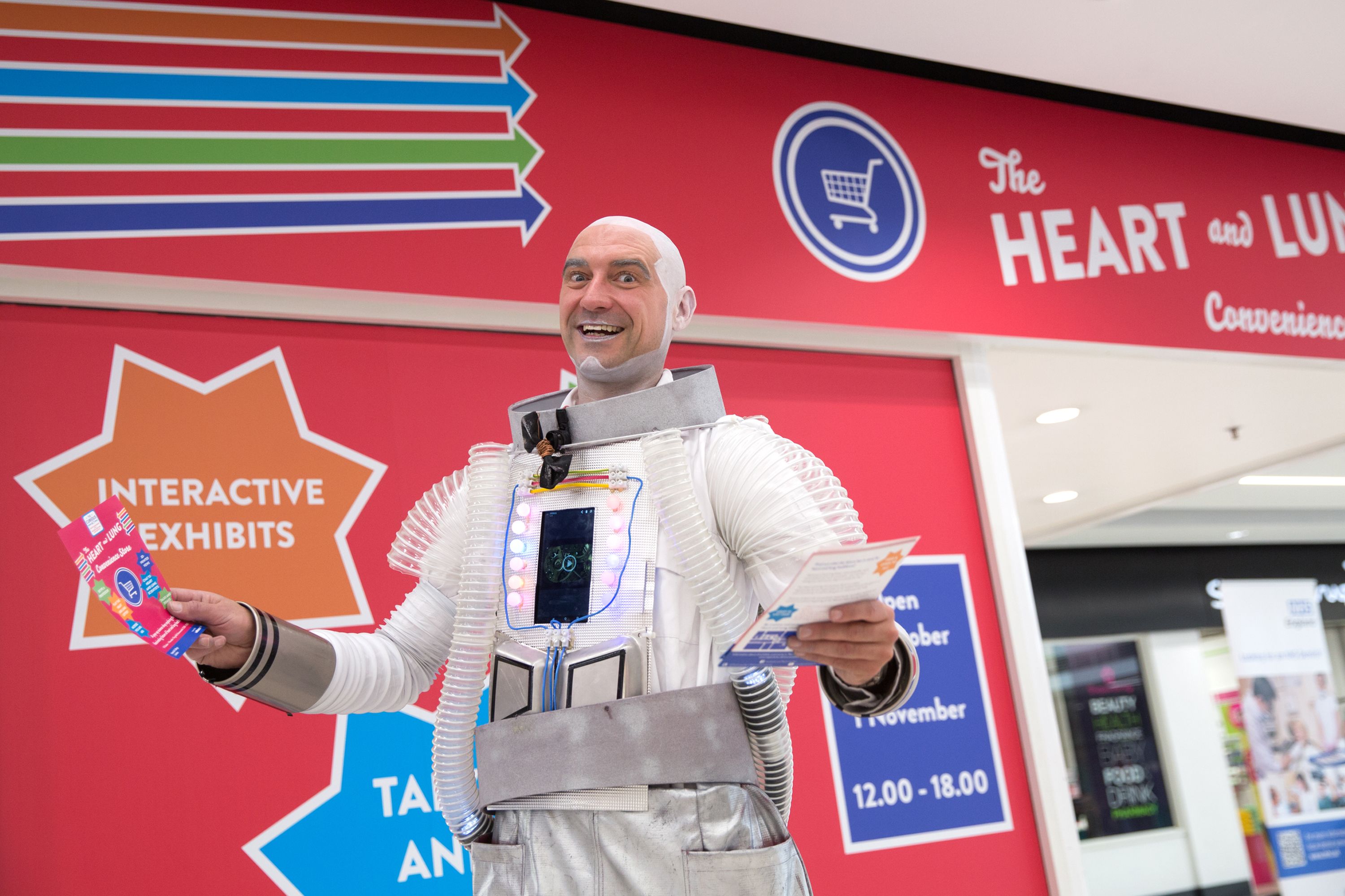 A smiling man dressed up as an astronaut holding a leaflet for the heart and lung popup