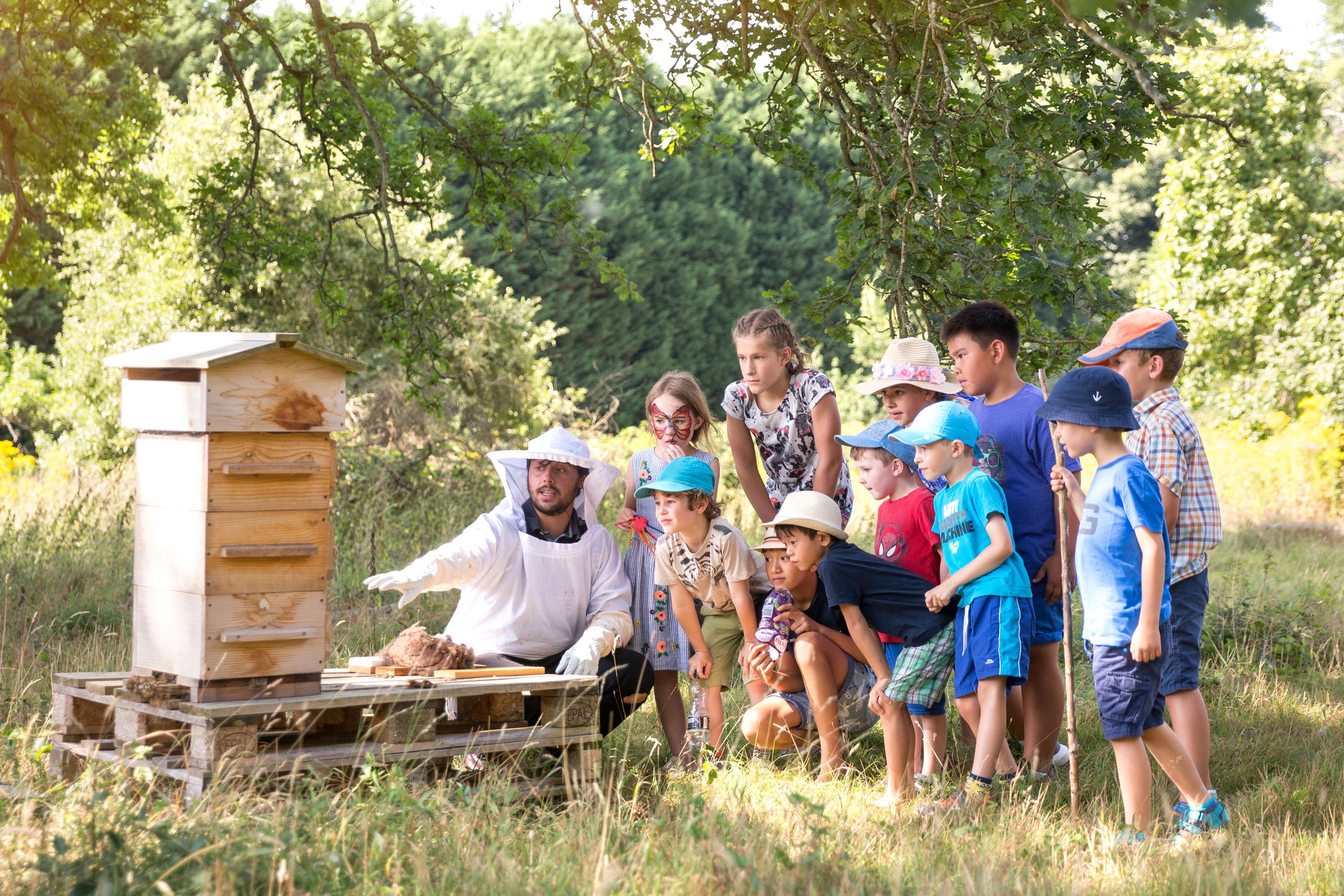 Children being shown a beehive by a beekeeper