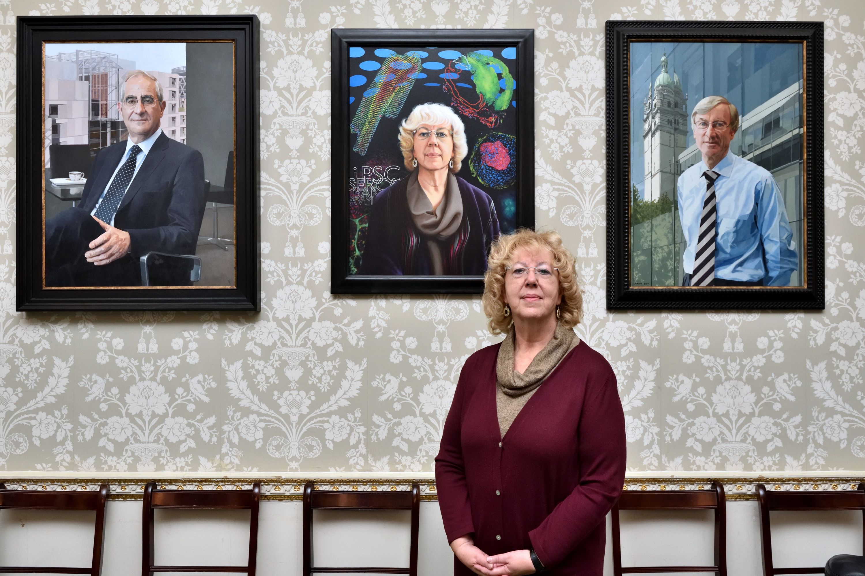 Emeritus Professor Sian Harding standing in front of her painted portrait