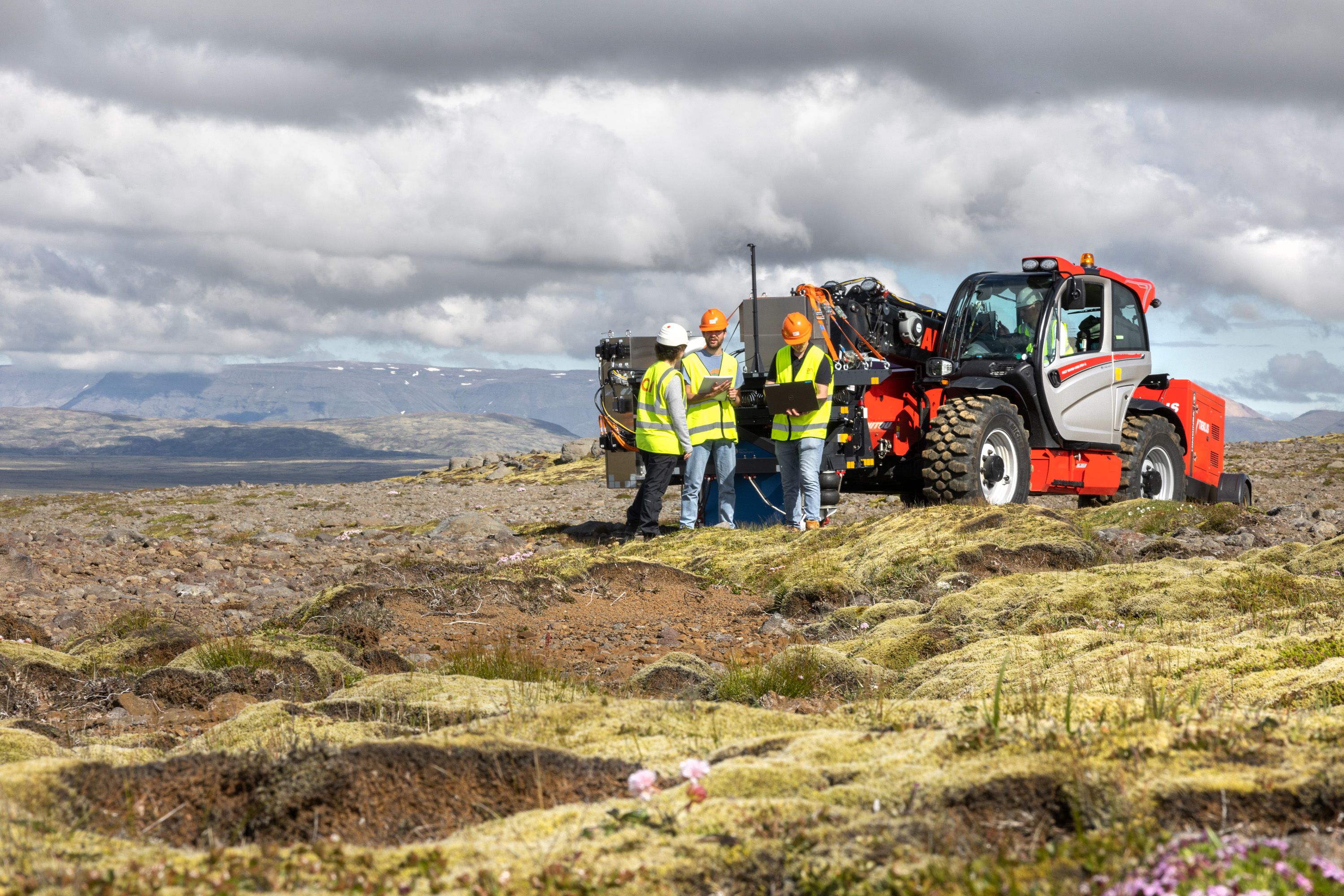 Men in high-vis vests with a modified tractor against the background of Icelandic mountains