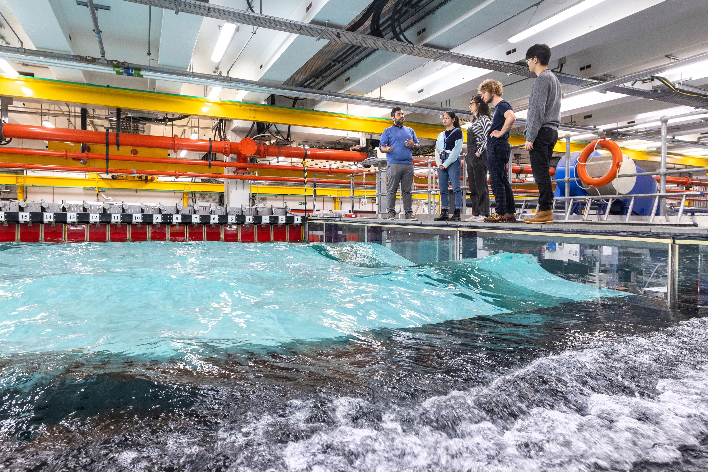 A lecturer talks to students as they stand on a platform above the wave tank