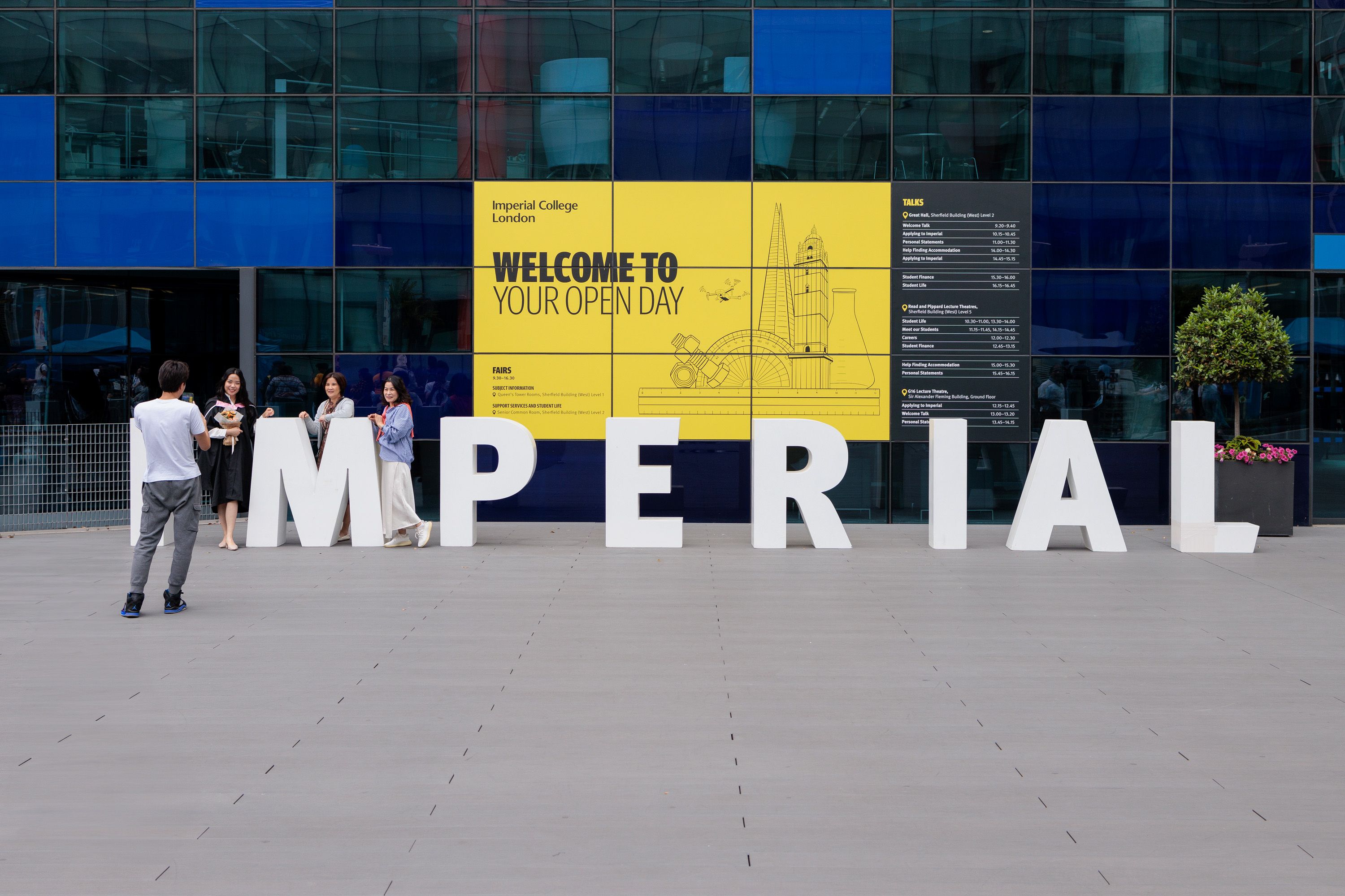 People posing for a photo in front of huge letters spelling the word Imperial, in front of a big sign saying Welcome to your Open Day