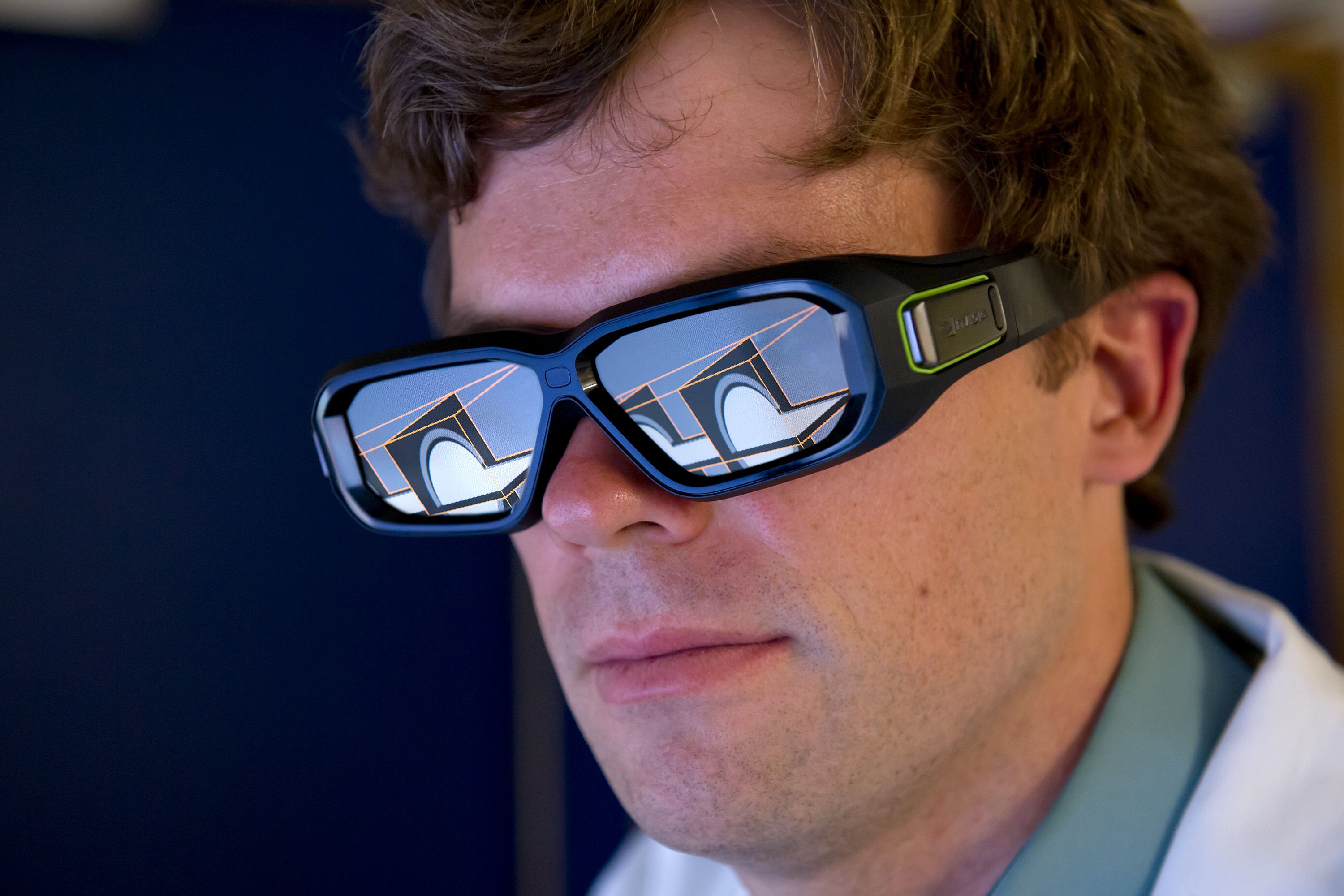 A man wearing big googles, on the lenses of which we see the bright lines and shapes of a computer visualisation
