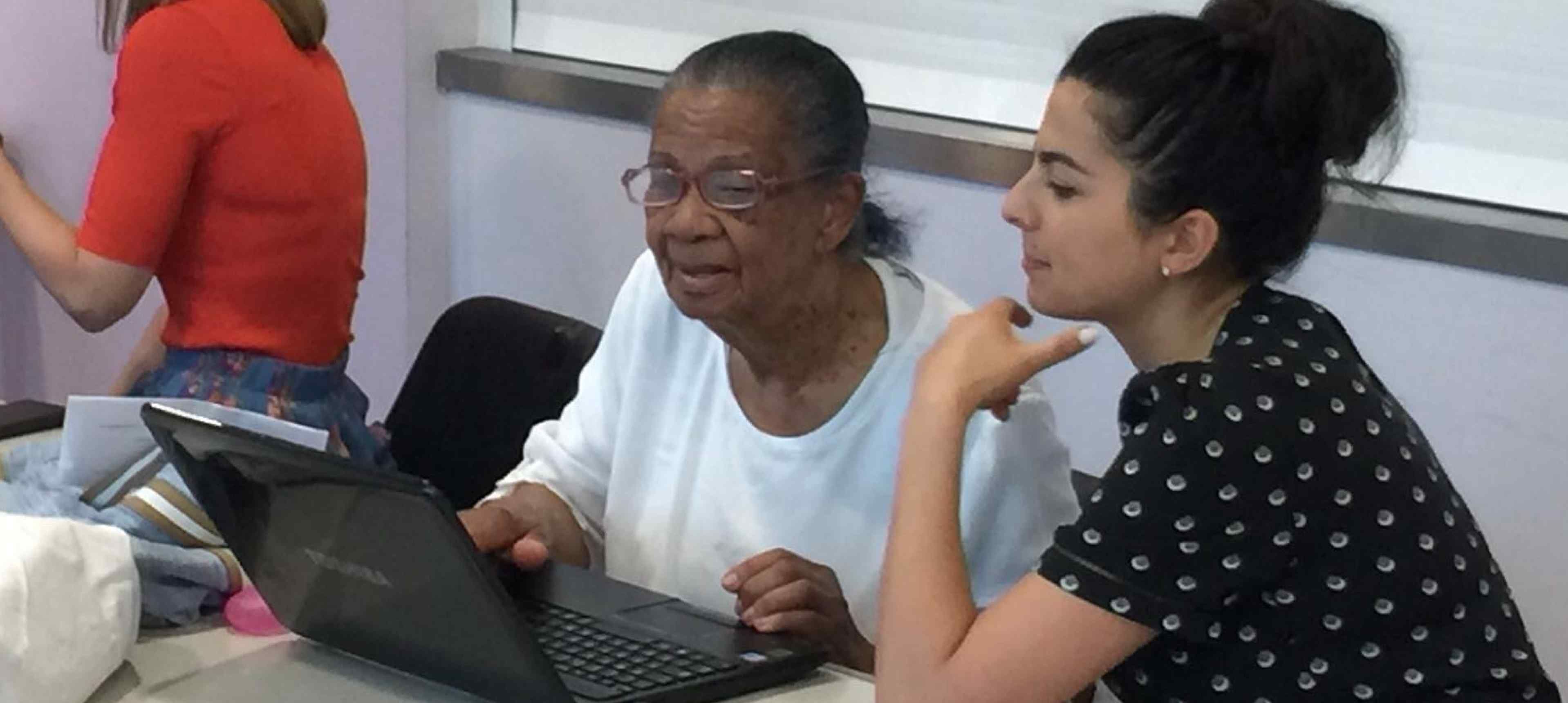 A local resident being shown how to use her laptop at What the Tech