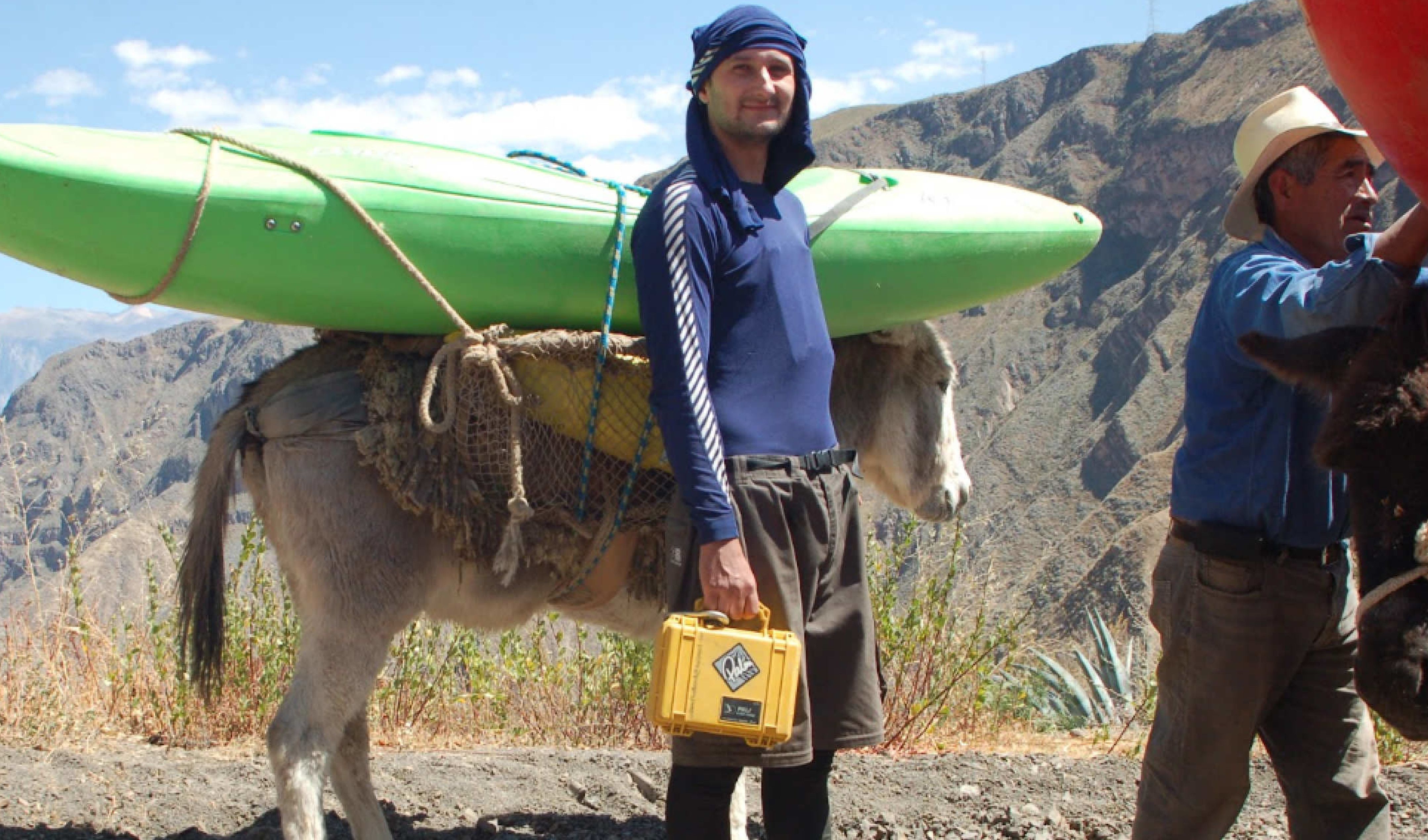 student with kayak on mule in background