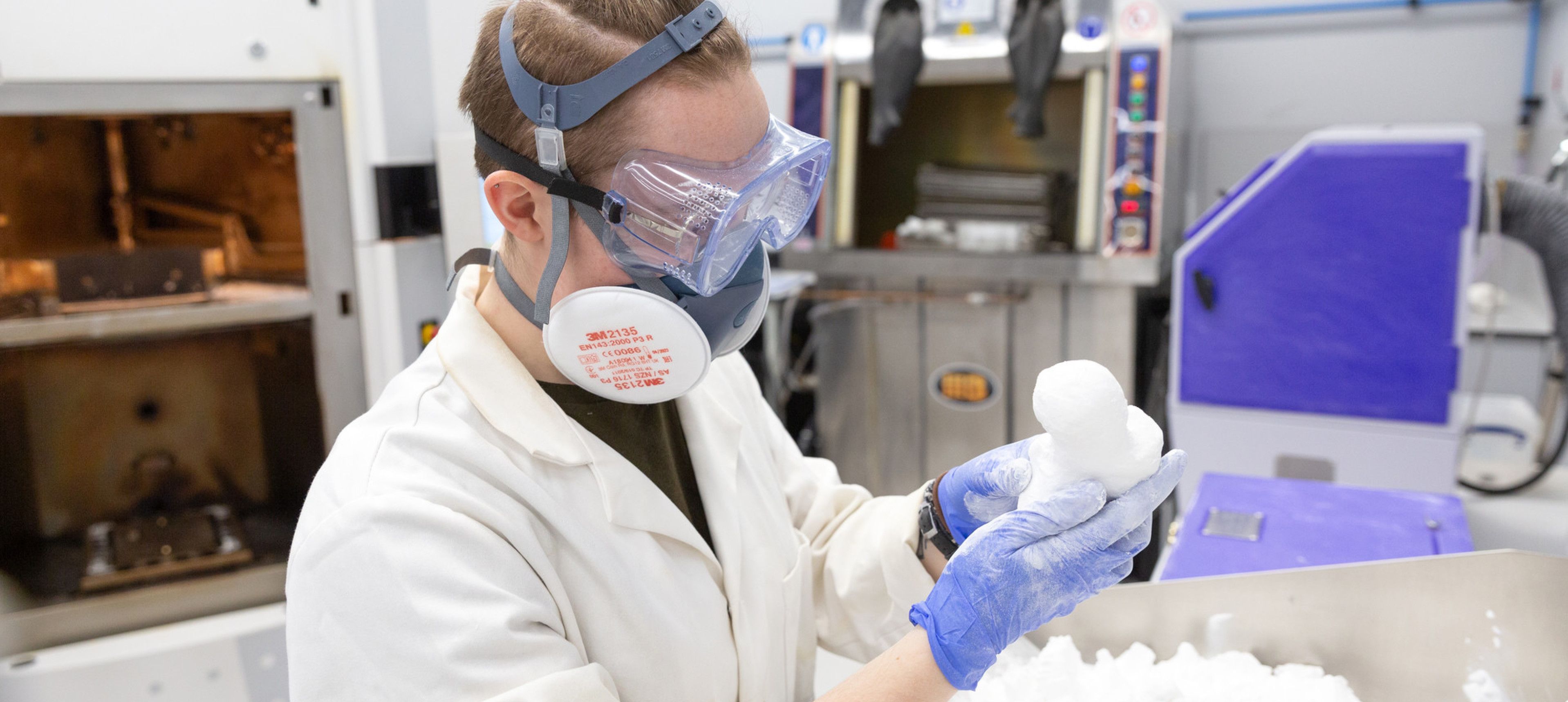 Researcher in MSk lab wearing PPE and holding a 3D printed object