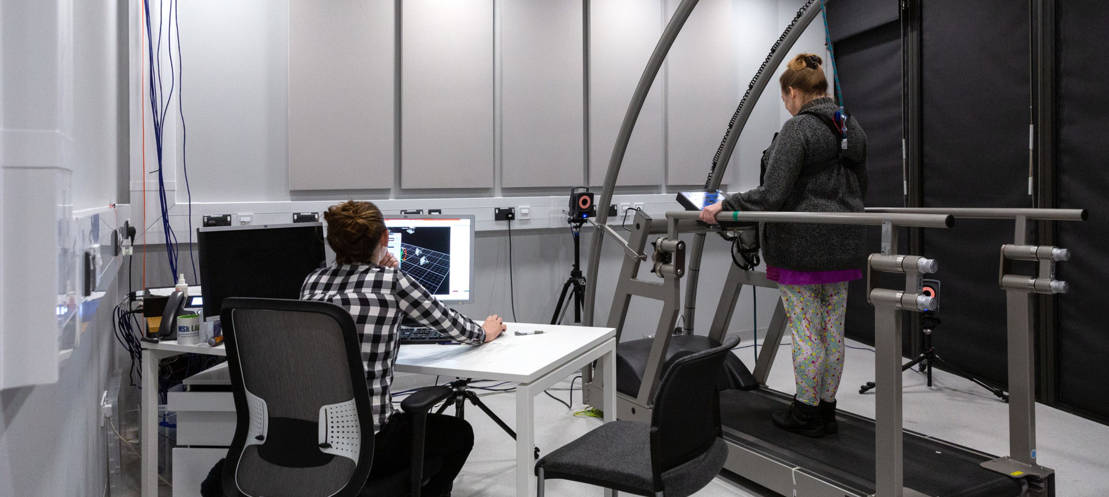 Researcher with willing participant on treadmill in the Gait Analysis lab