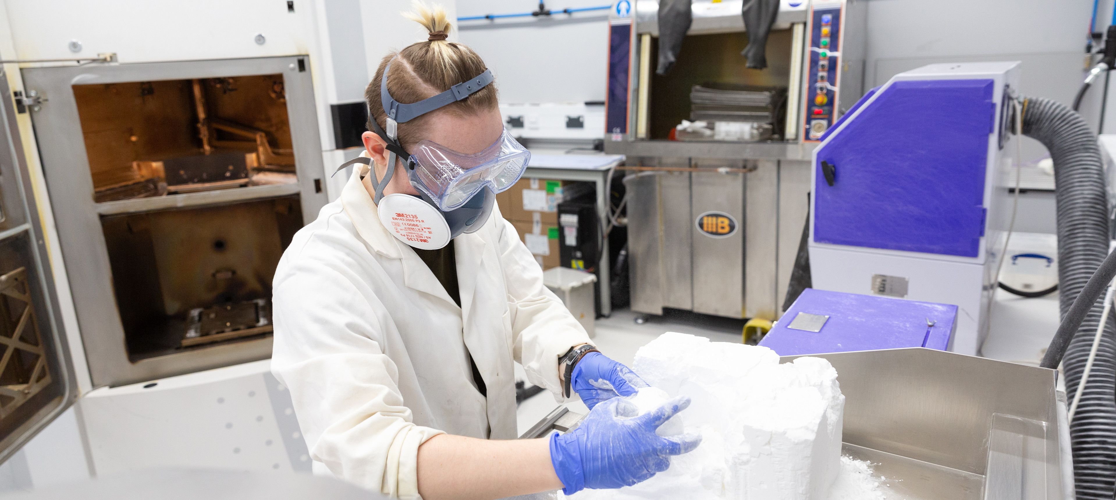 A scientist in a lab working on a 3D printed surgical guide partial knee operations wearing PPE