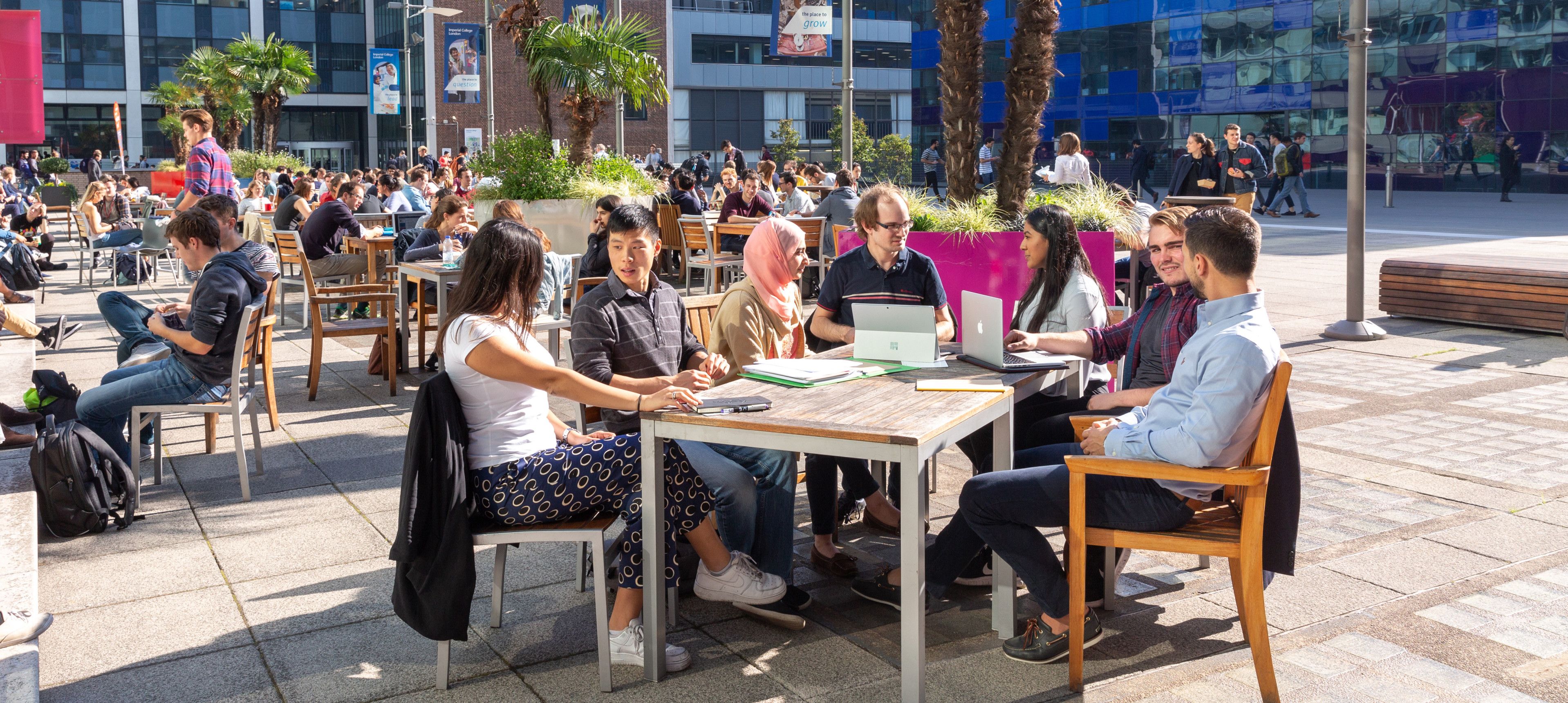 Imperial students sitting at a table in the sunshine in Dalby Court