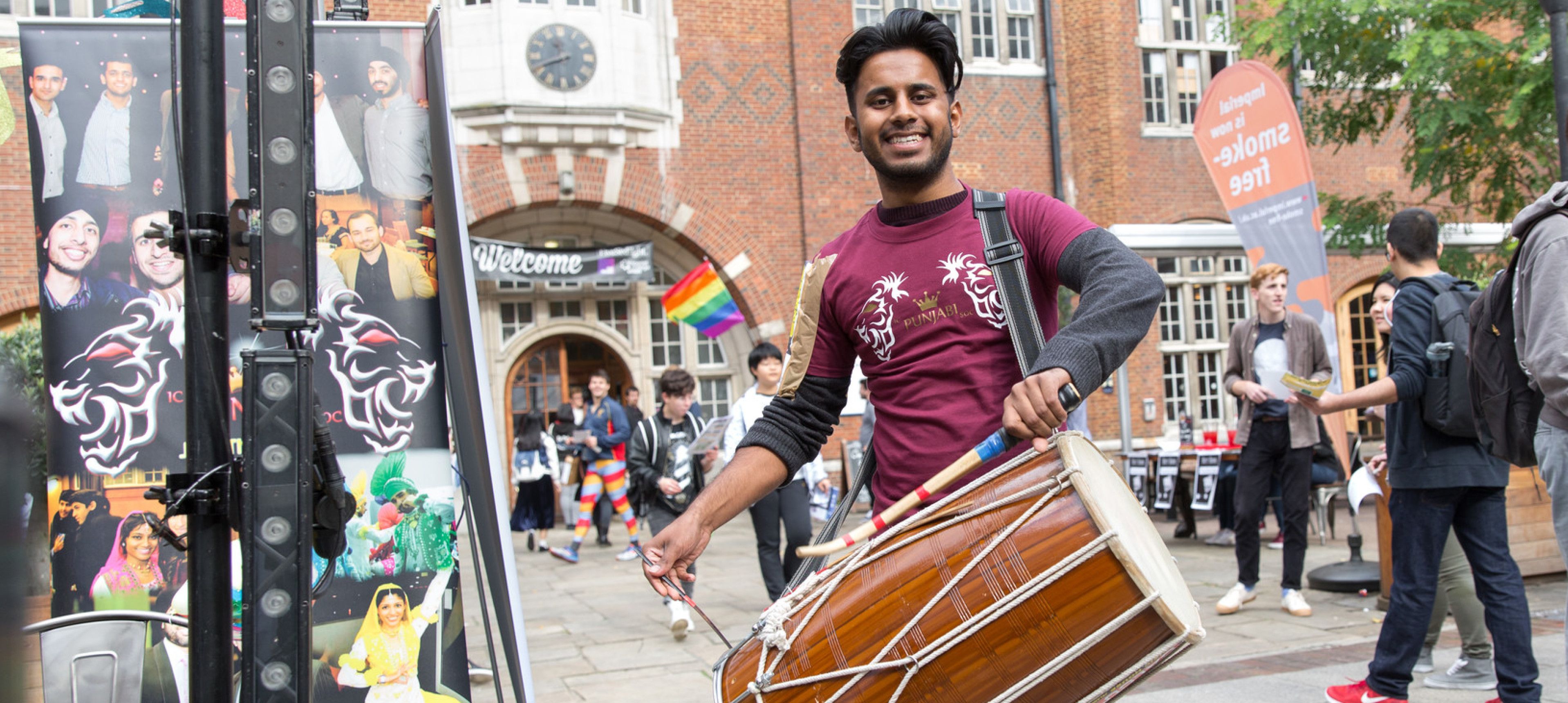 A student playing a drum at Imperial College London Welcome Fair