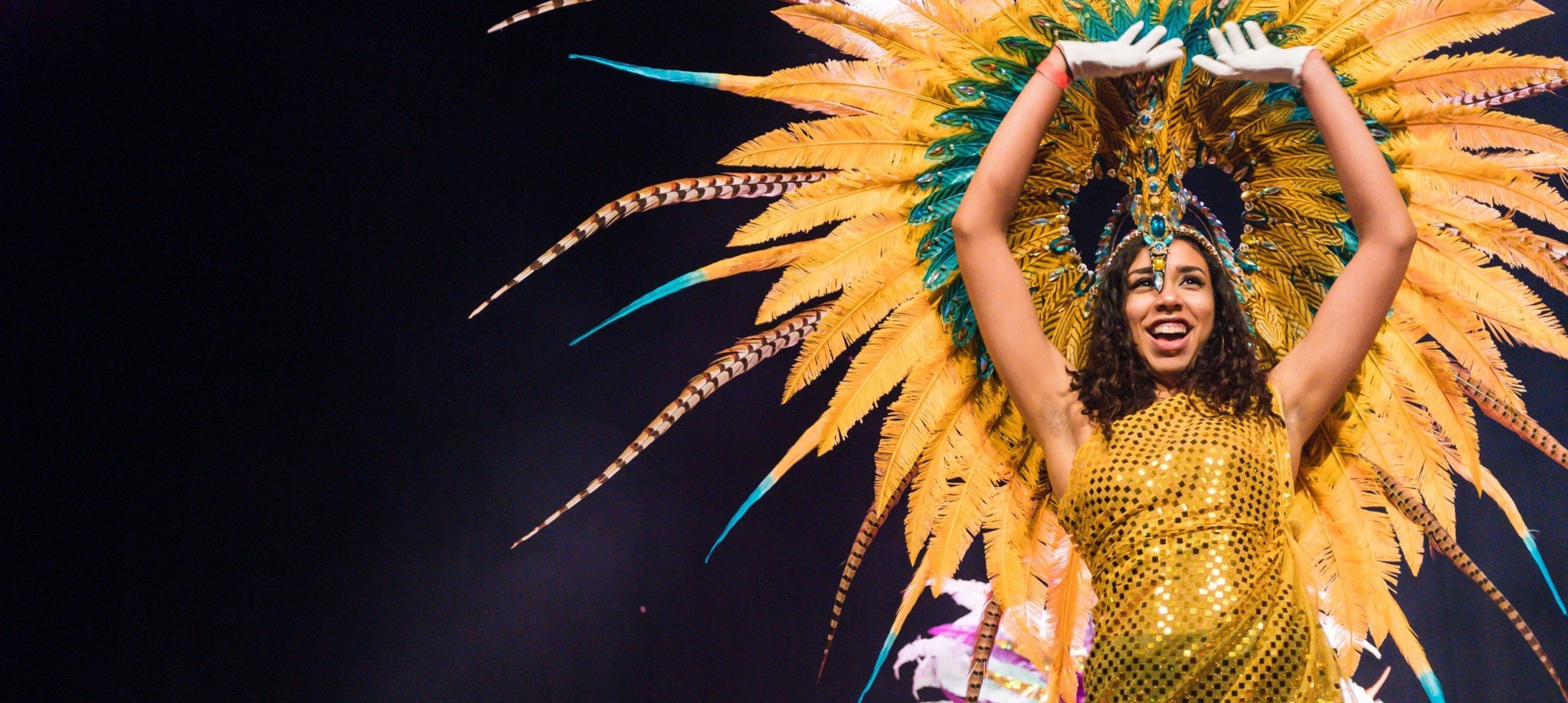 A student wearing a sparkly yellow dress and large headress at Imperial's Afrogala celebration