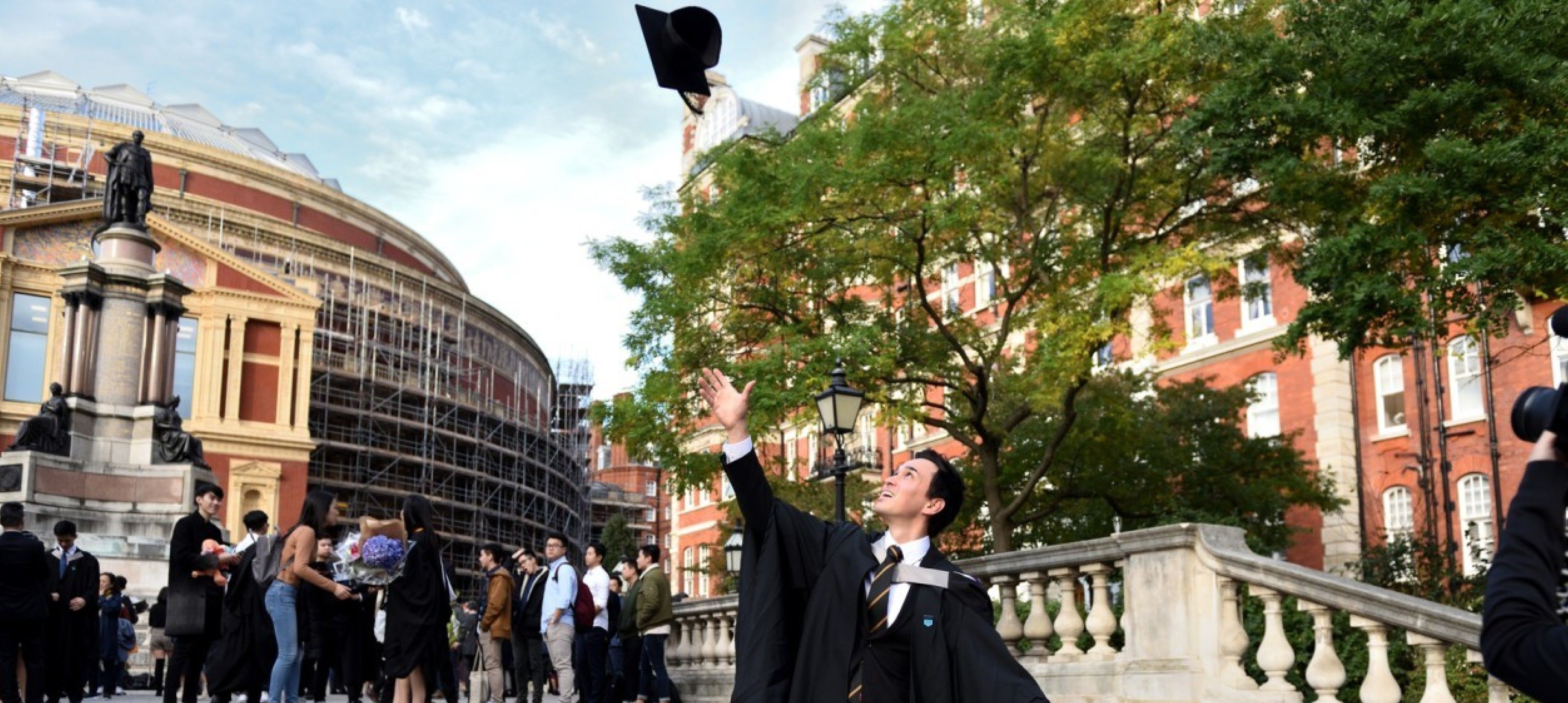A graduand throwing his mortar board in the air on the steps in front of the Royal Albert Hall