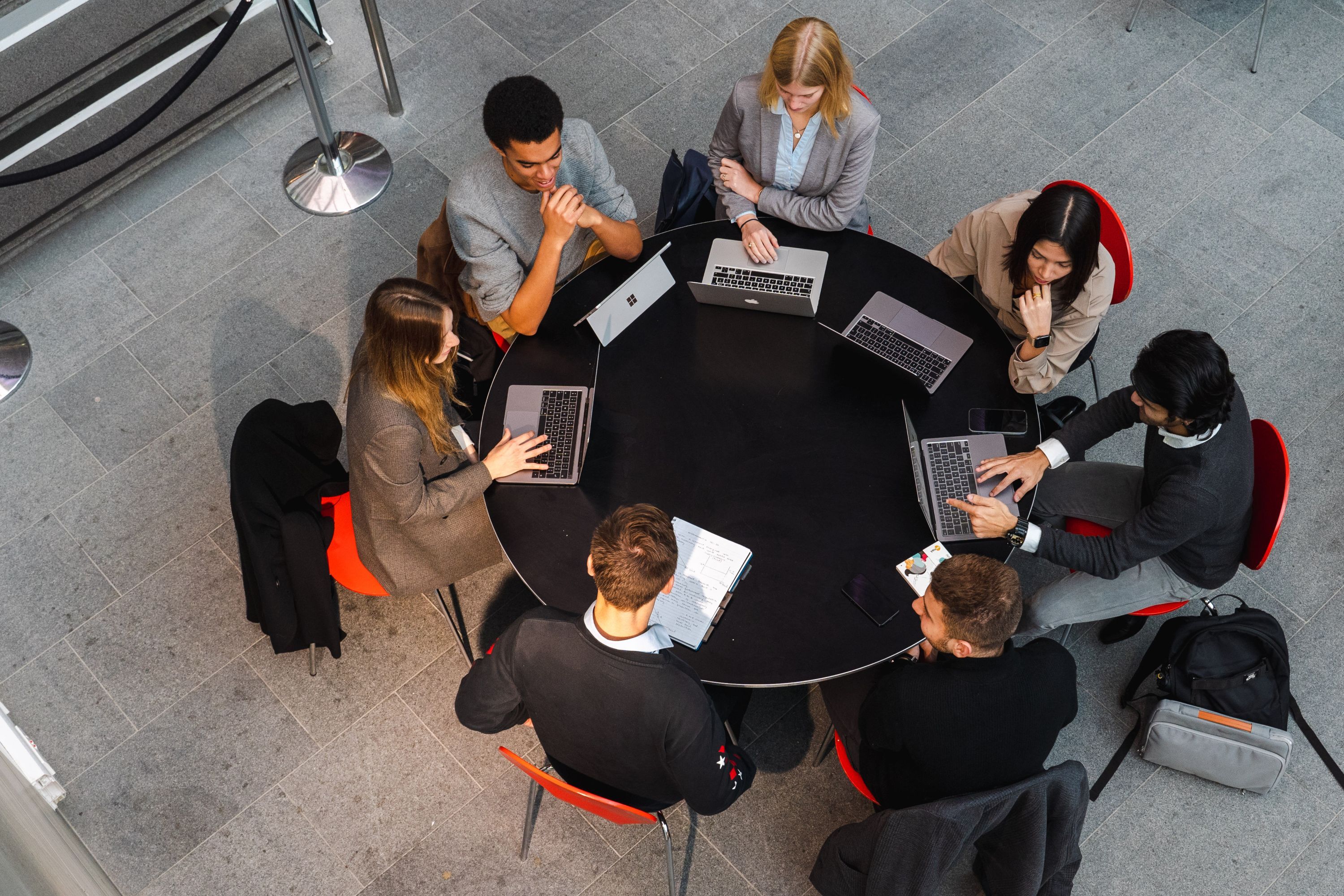 A group of students sat on a round table on their laptops