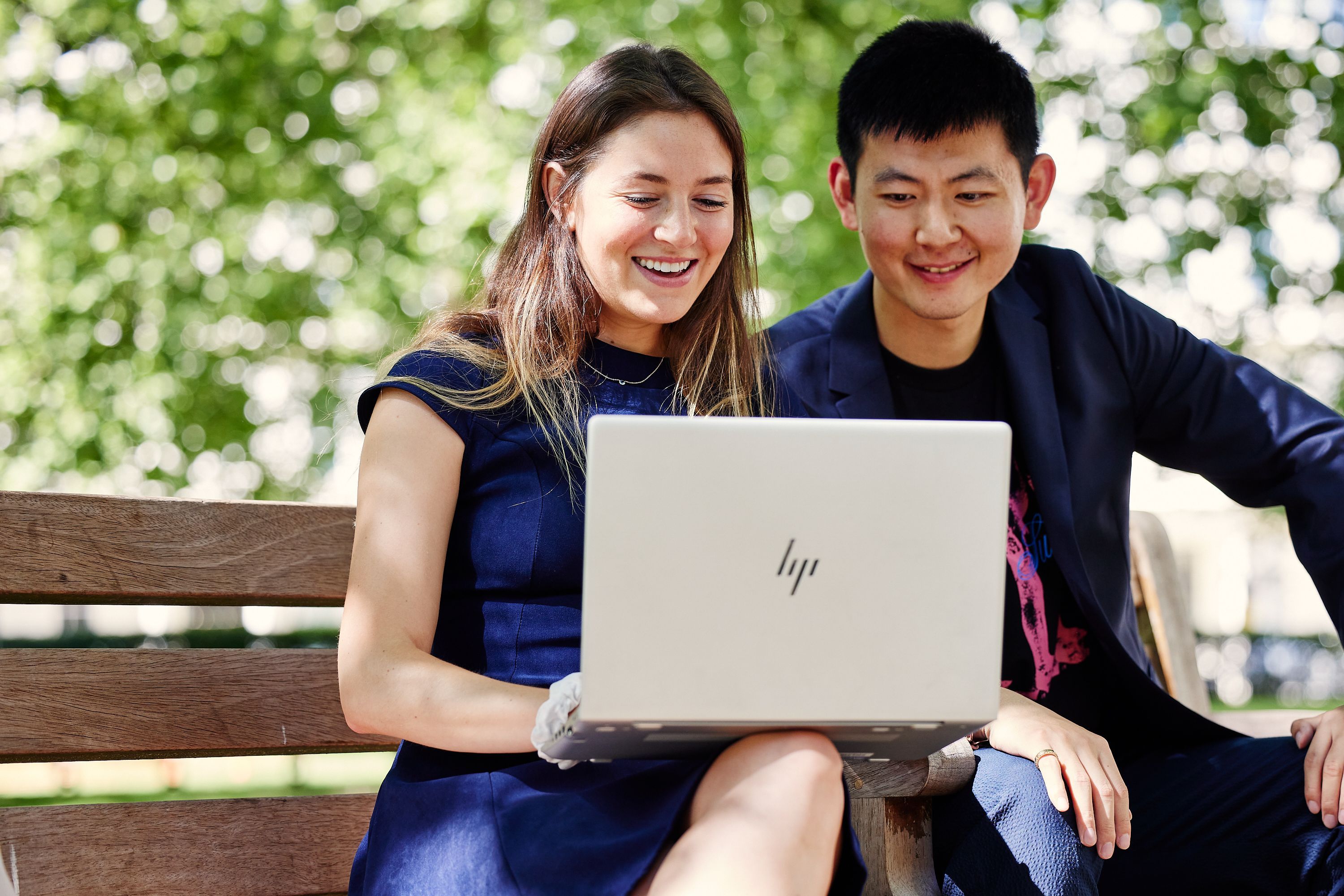 Two students outside looking at a laptop