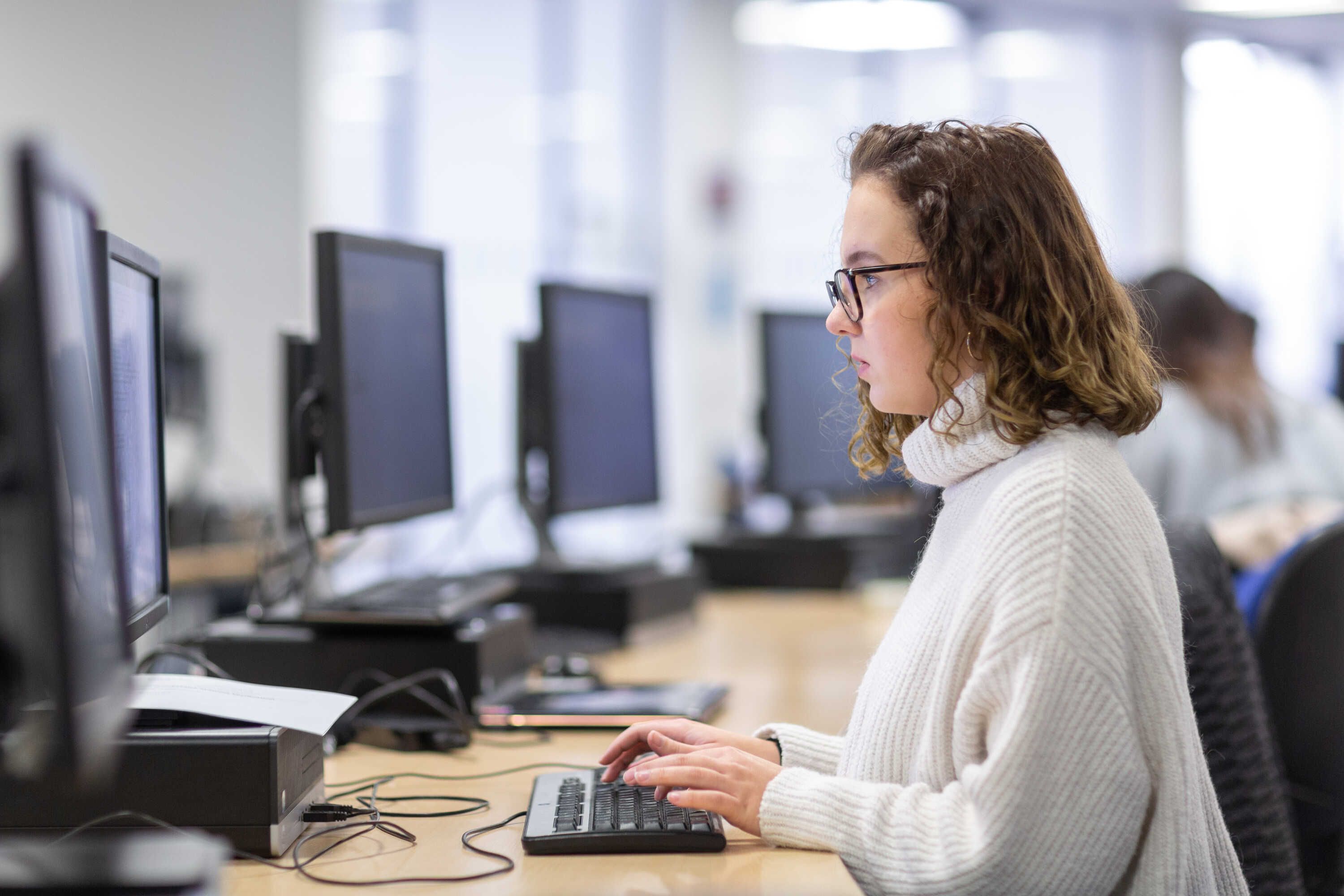 a female student working on a computer in a computer lab