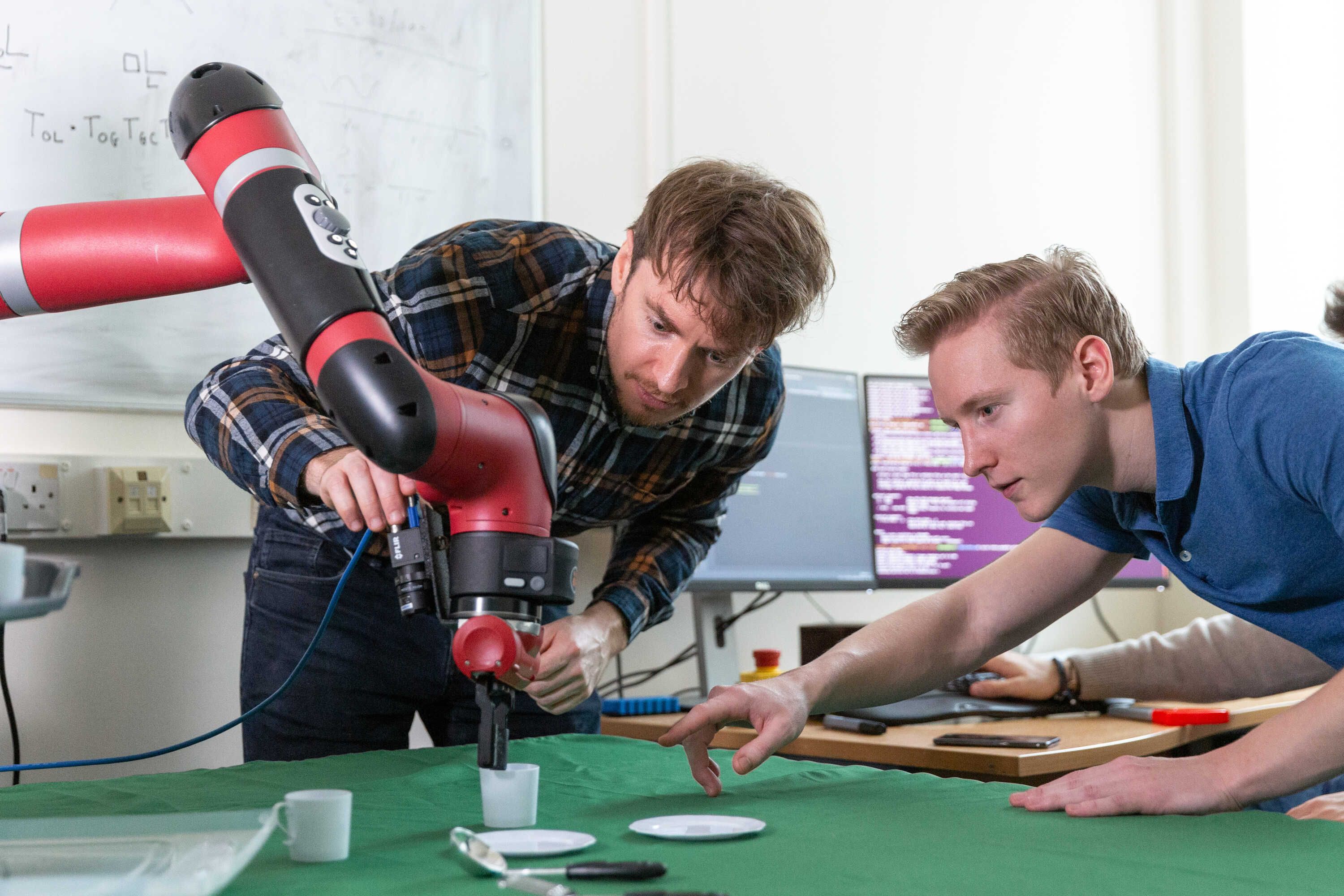 two students working pointing at a red robot