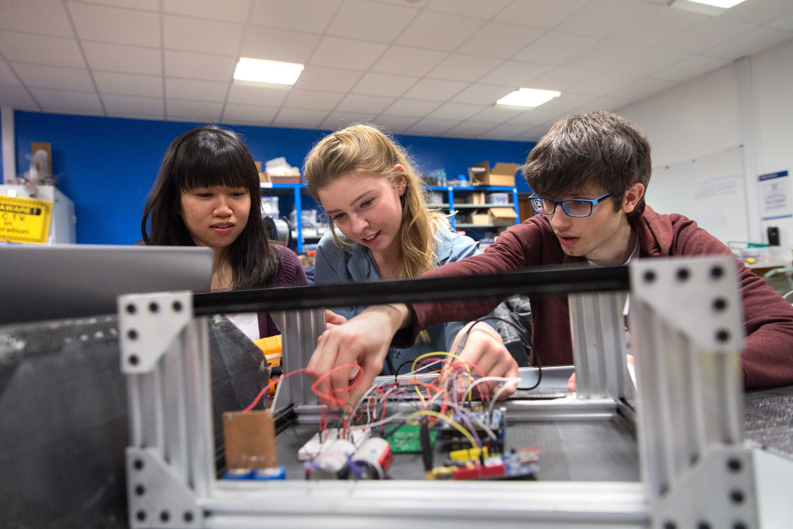 Three EEE students working on electronics