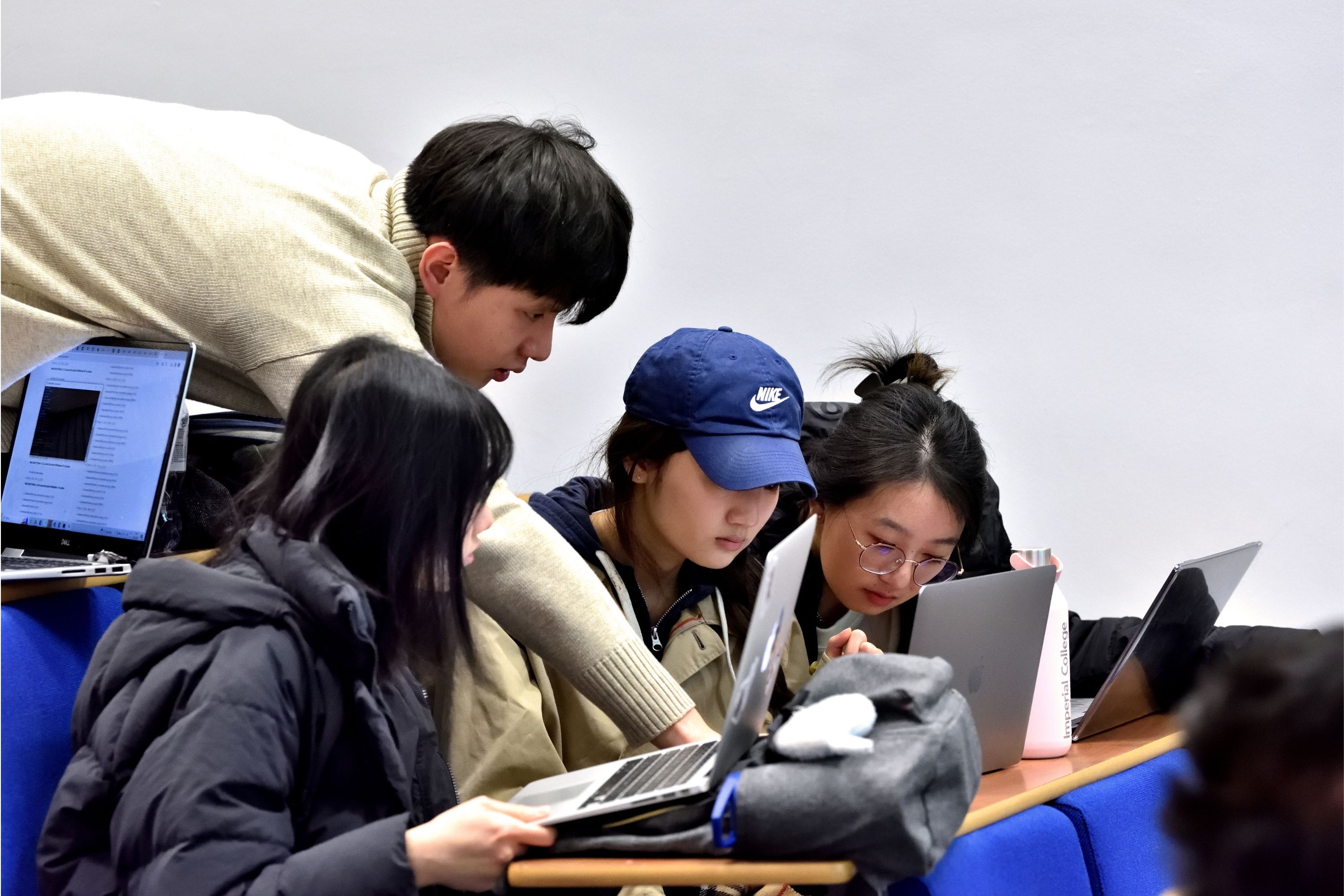 three students looking at a laptop and smiling