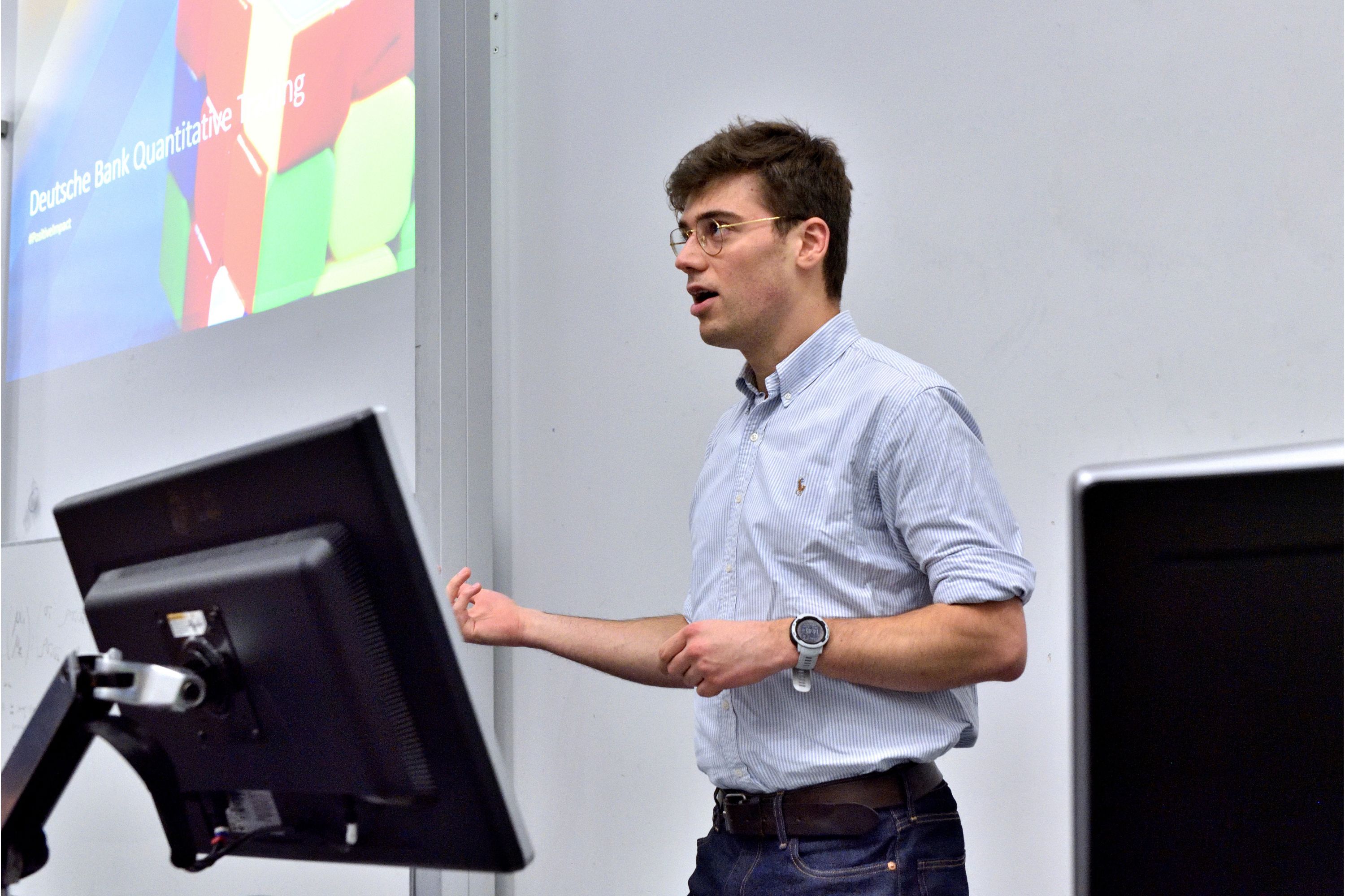 a male lecturer presenting in front of a screen