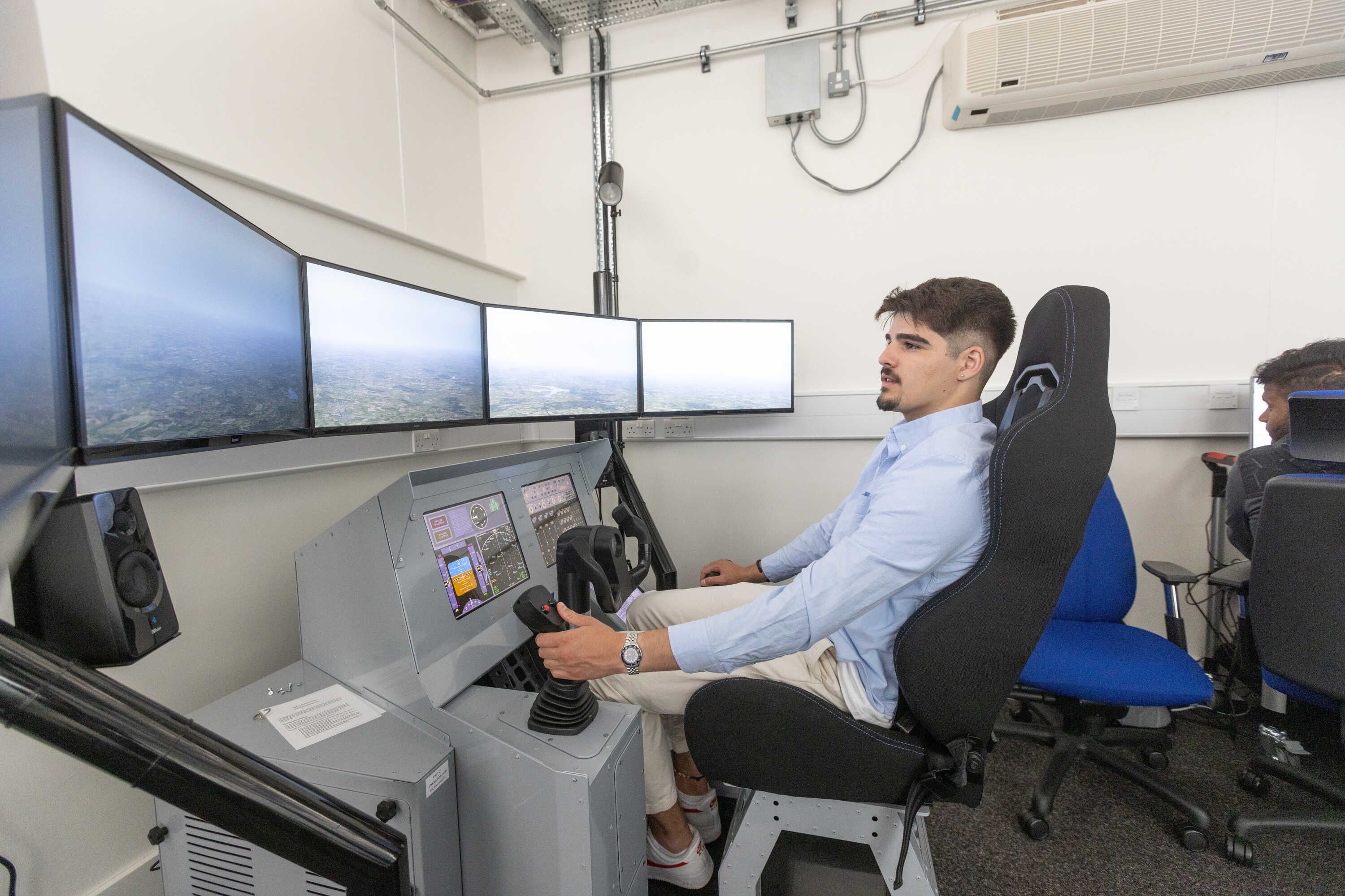 A male student operating a flight simulator machine
